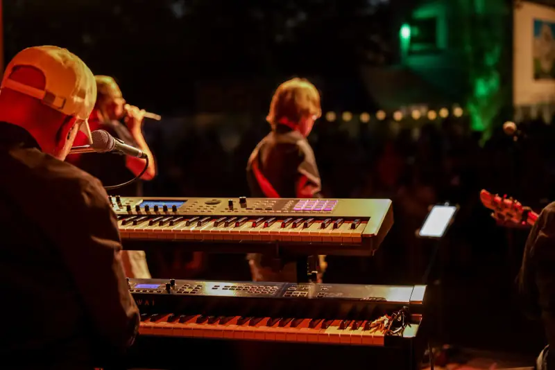 Band bei Nacht auf der Open-Air-Bühne, Keyboard im Vordergrund Band bei Nacht auf der Open-Air-Bühne, Keyboard im Vordergrund